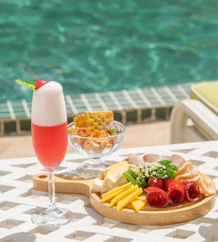 Cocktail và đĩa đồ ăn nhẹ bên hồ bơi